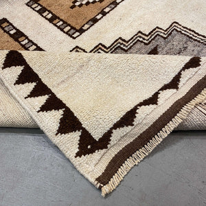Folded edge of Aksaray Vintage Wool Rug on a gray floor - H+E Goods Company