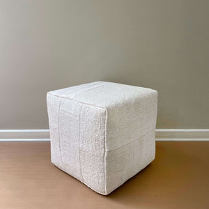 Asmia Vintage Hemp Patchwork Pouf on its side on a light brown floor and a beige wall - H+E Goods Company