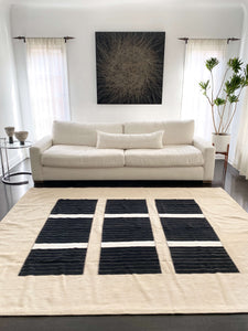 Kinik Modern Flat-Weave Rug in front of white sofa on a dark brown floor - H+E Goods Company