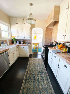 Lifestyle view of Muzaran Vintage Malayer Rug on dark brown floor in the kitchen - H+E Goods Company