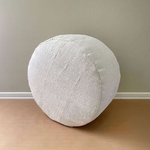 Senet Vintage Patchwork Hemp Pouf on its side on a light brown floor and a beige wall - H+E Goods Company