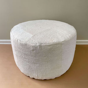 Alternate front view of of the Senet Vintage Patchwork Hemp Pouf on a light brown floor and a beige wall - H+E Goods Company