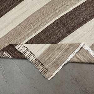 Folded edge of Parwan Kilim Rug on gray floor - H+E Goods Company
